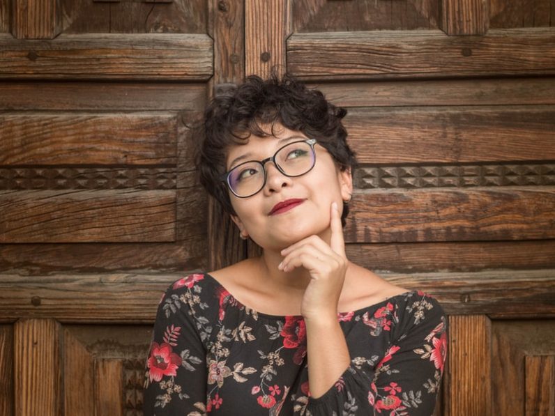 Photo par Paola Aguilar woman leaning against door while holding her cheek